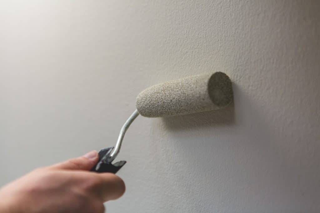 Hand rolling primer on wall with paint roller