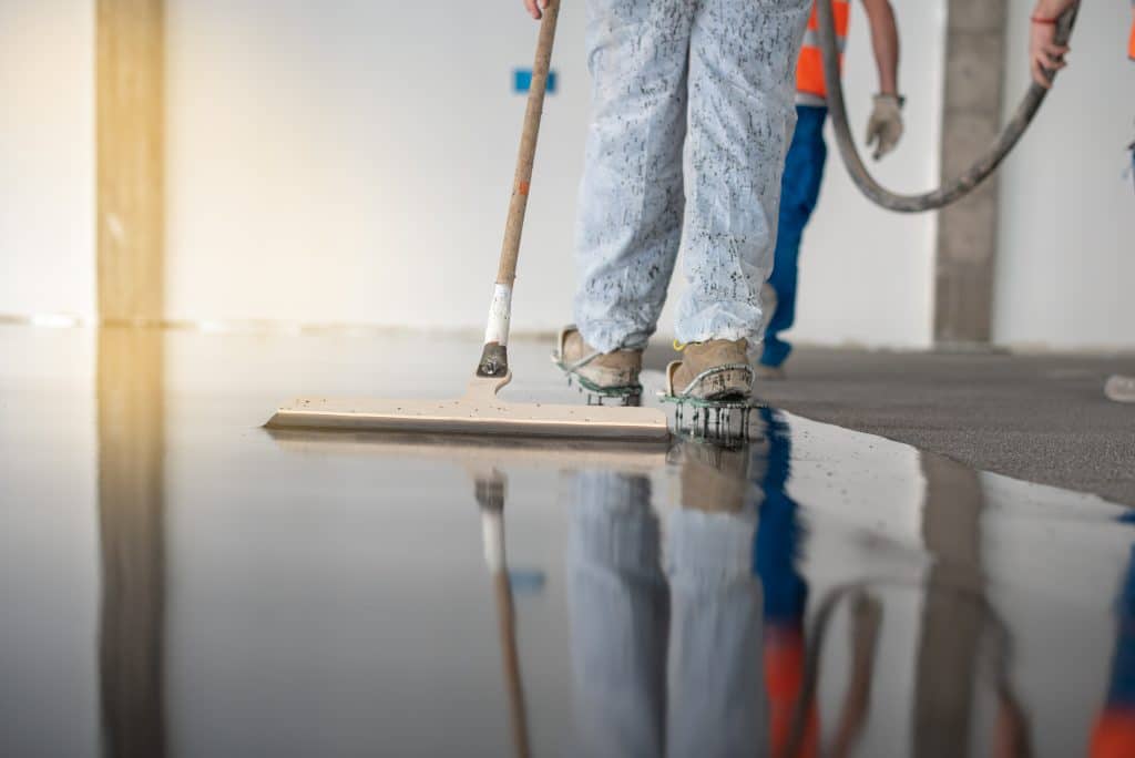 Epoxy resin being applied to garage floor by worker wearing protective shoes