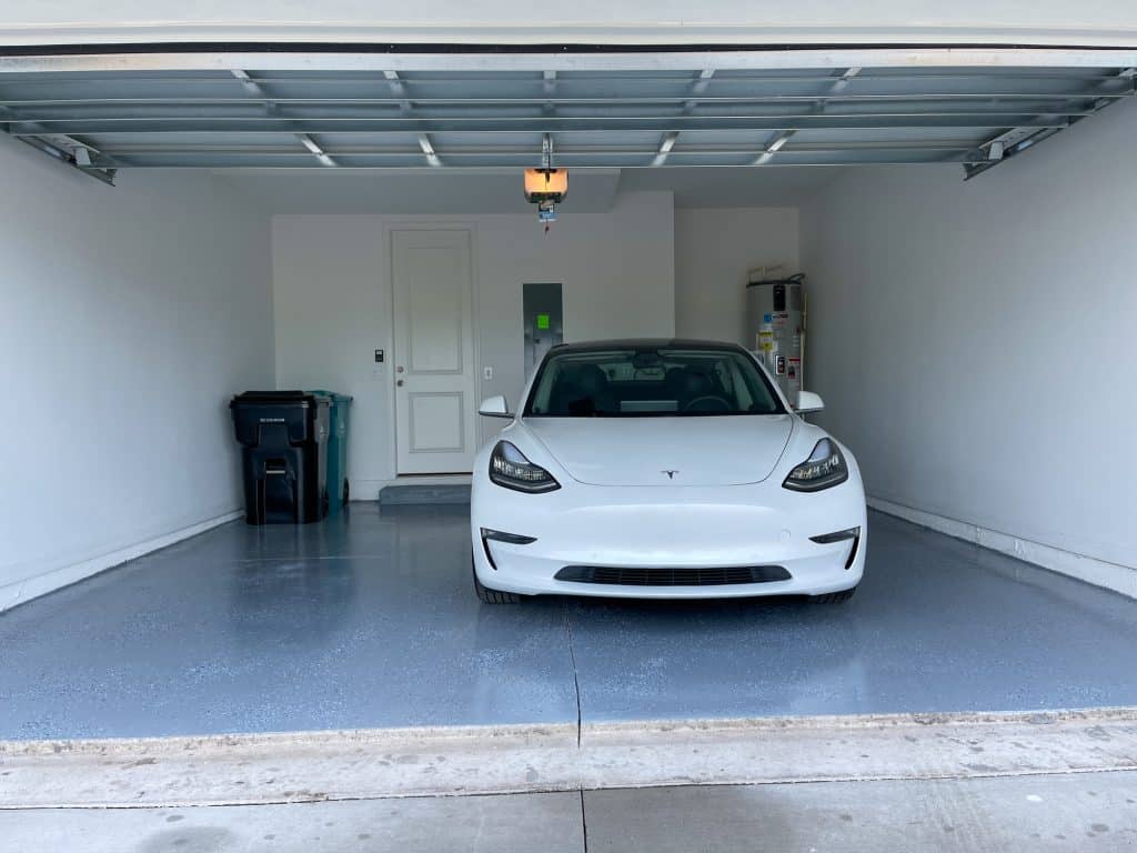 Tesla parked in garage with blue epoxy flooring